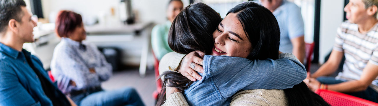 Mid adult women embracing in a group therapy