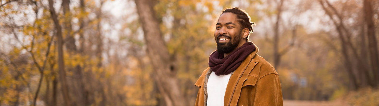 Young African American man walking in nature on beautiful autumn day.