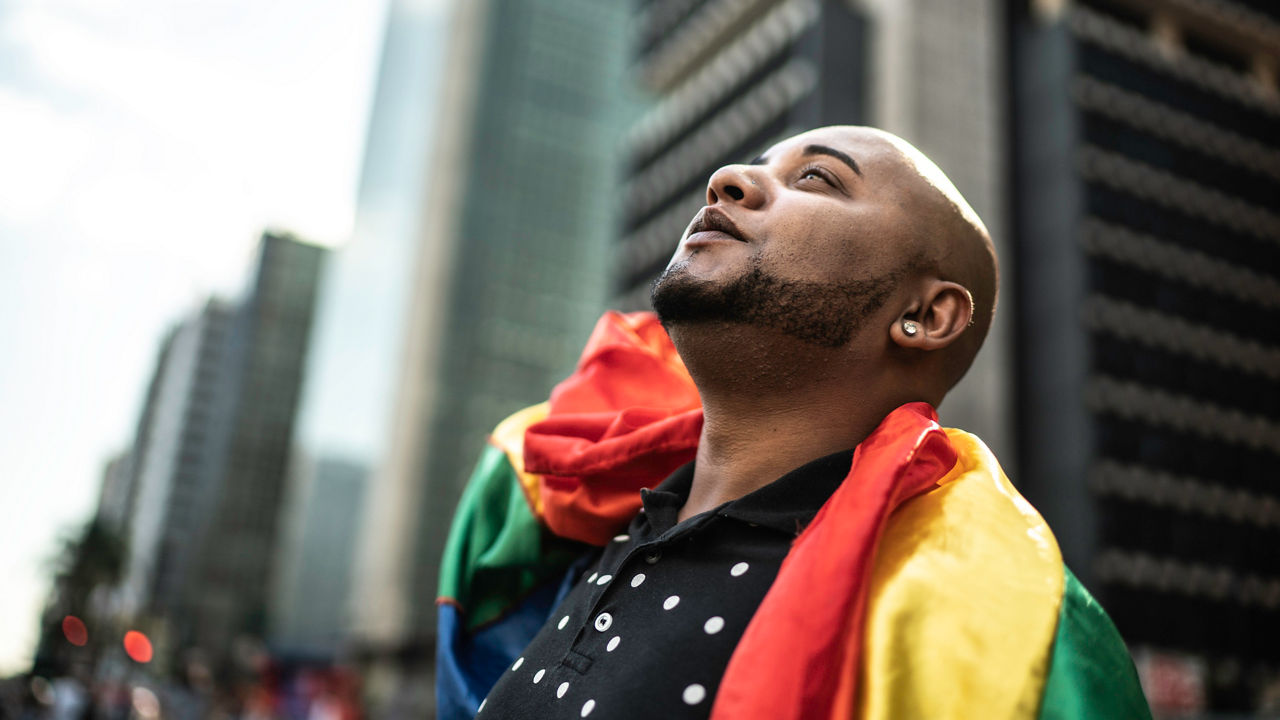 Young gay man holding rainbow flag during pride parade