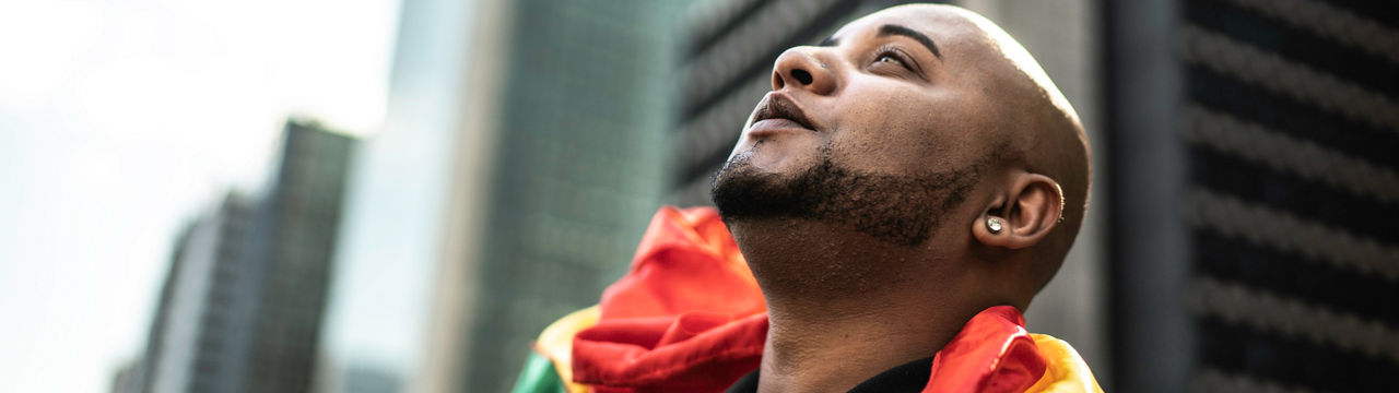 Young gay man holding rainbow flag during pride parade