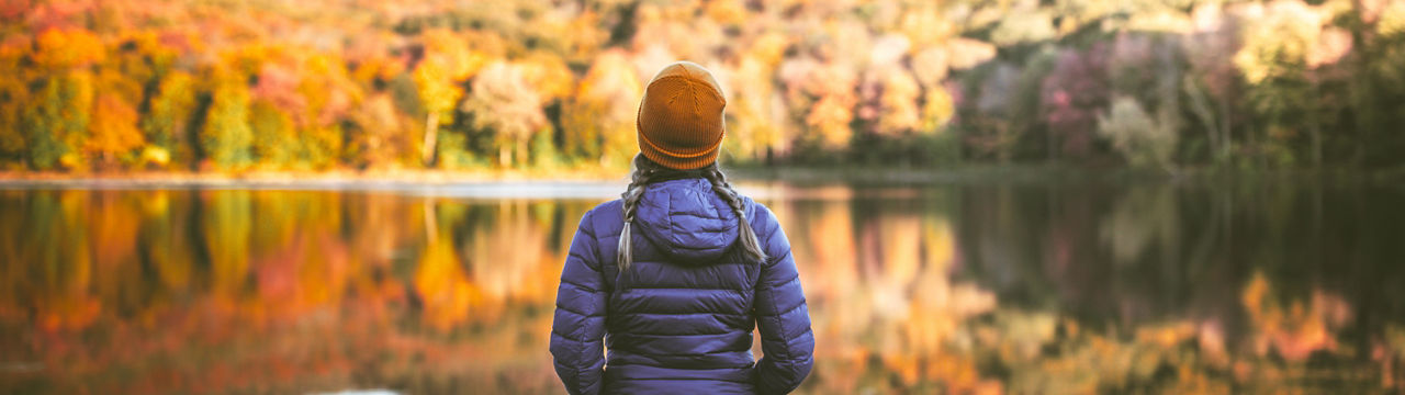 Young woman in autumn by lake, Serene young woman alone in nature surrounded by beautiful autumn colors.