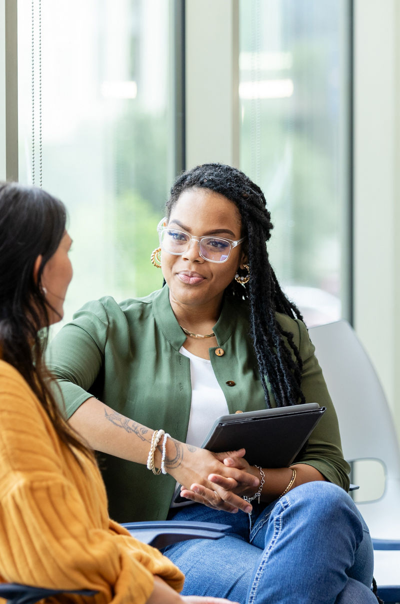An unrecognizable young adult woman shares her problems with the young adult female counselor.