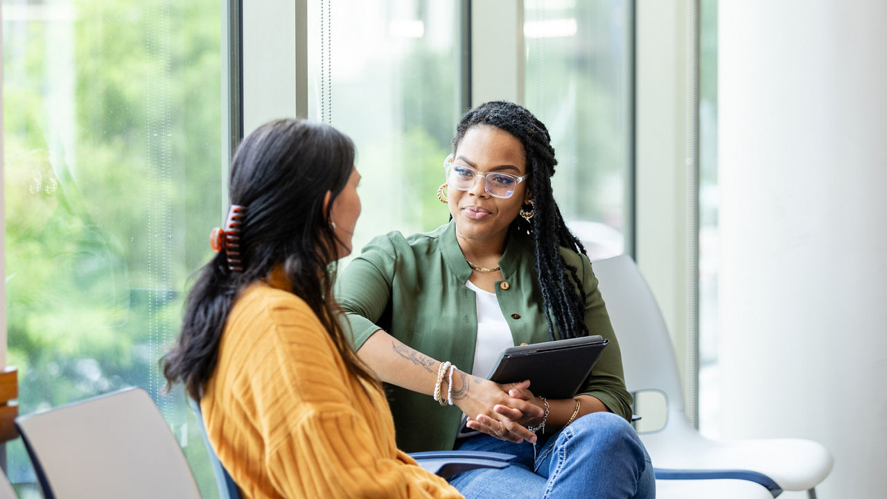 An unrecognizable young adult woman shares her problems with the young adult female counselor.