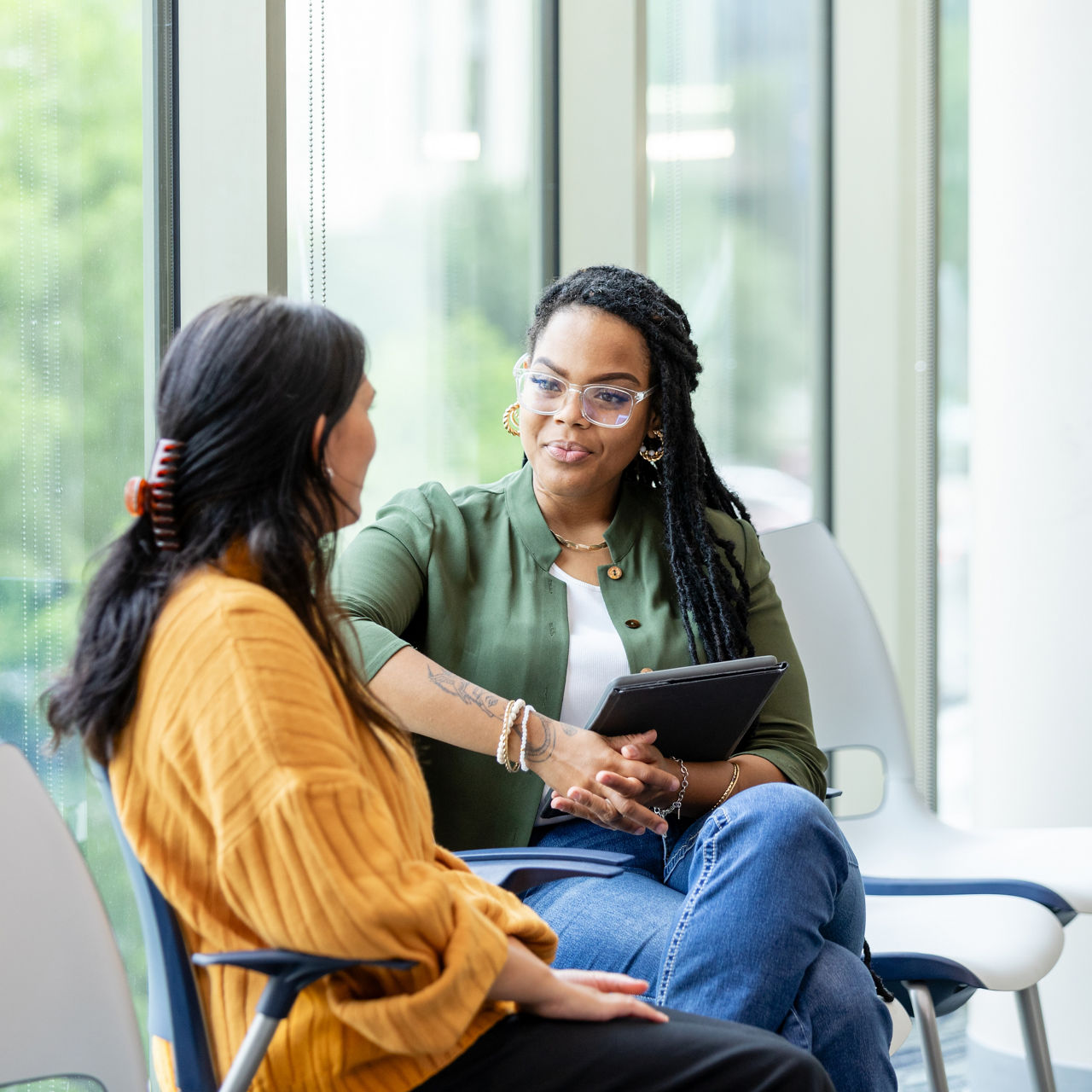 An unrecognizable young adult woman shares her problems with the young adult female counselor.