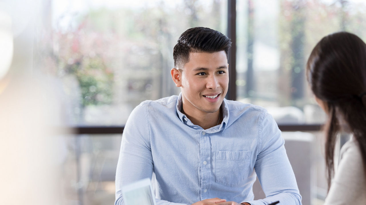 A confident mid adult male job applicant smiles as he listens to a potential employer describe the position 