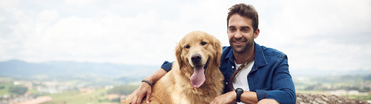Cropped shot of a handsome young man sitting on a rock with his golden retriever after a day out hiking 