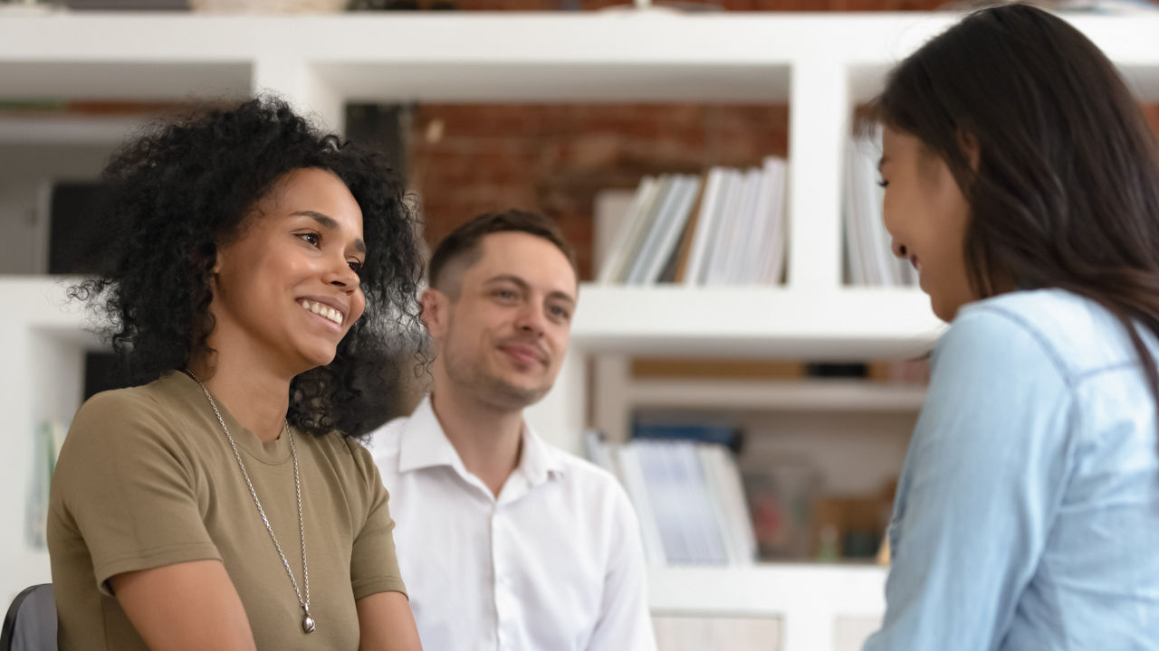 Asian and African American women holding hands during group therapy session, diverse friends feeling reconciled relief smiling giving psychological support empathy overcome problem at psychotherapy counseling.