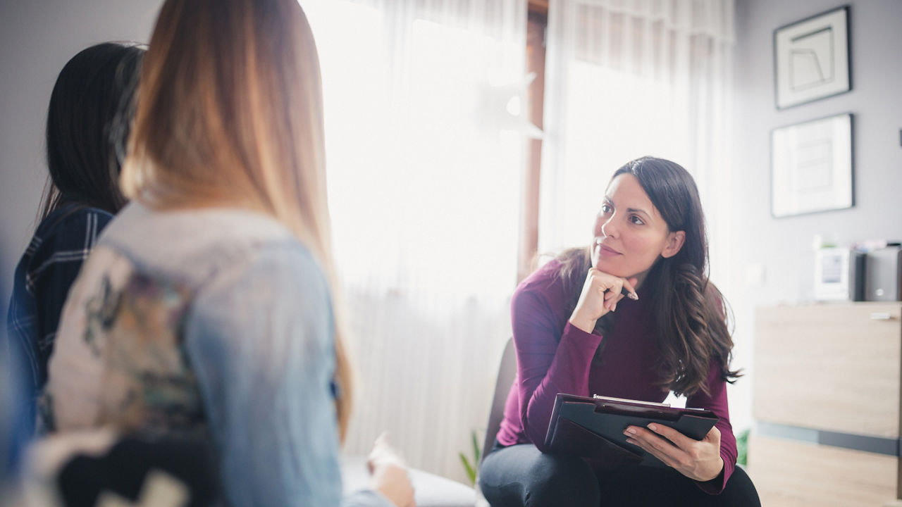Counselor advising young lesbian couple at their home