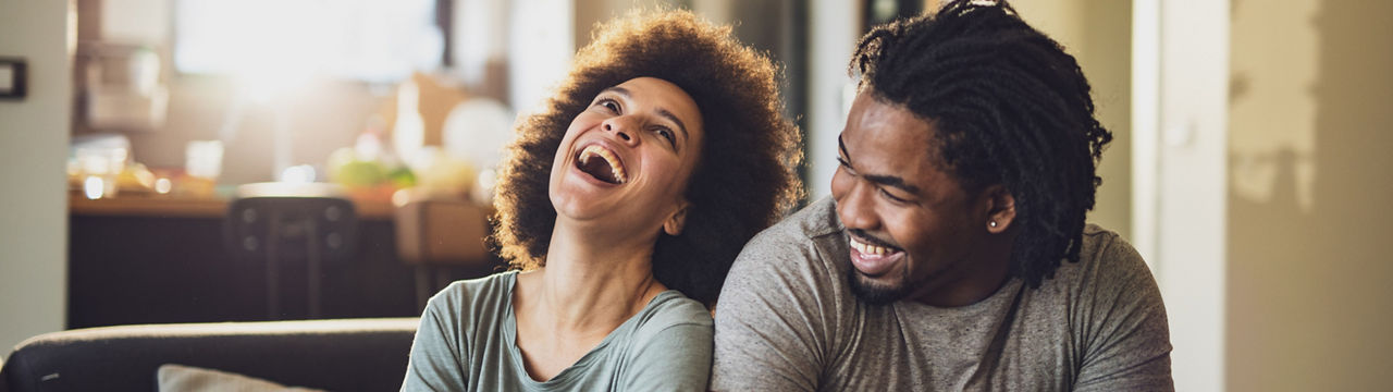 Cheerful African American couple having fun while relaxing on sofa at home