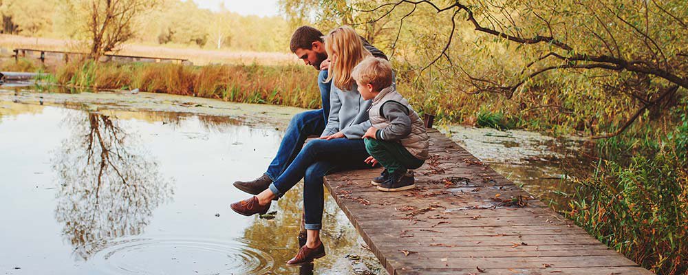 Family sitting on a bridge with their feet in the water