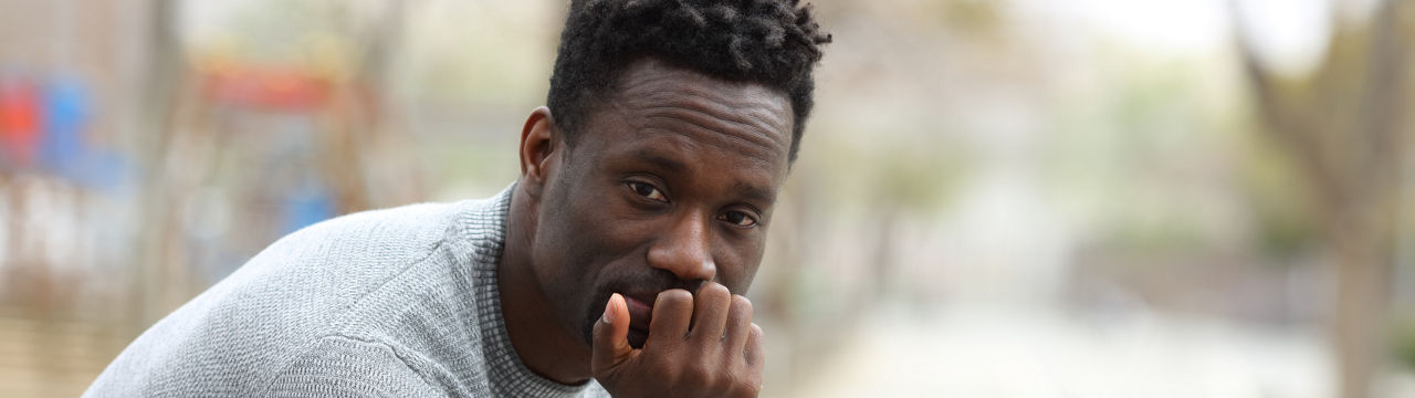 Portrait of a serious African American man looking at camera sitting in the park bench