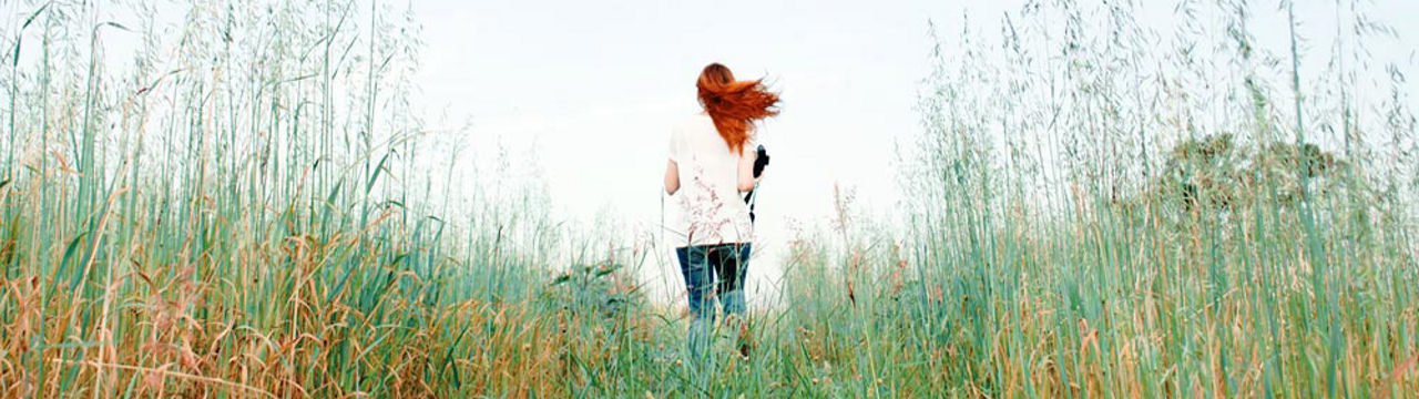 Female with red hair running in meadow