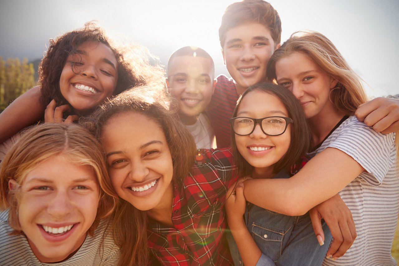 Teenage school friends smiling to camera, close up