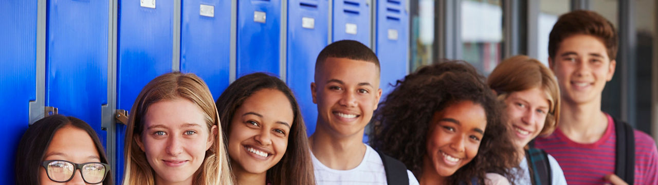 Teenage school kids smiling to camera in school corridor