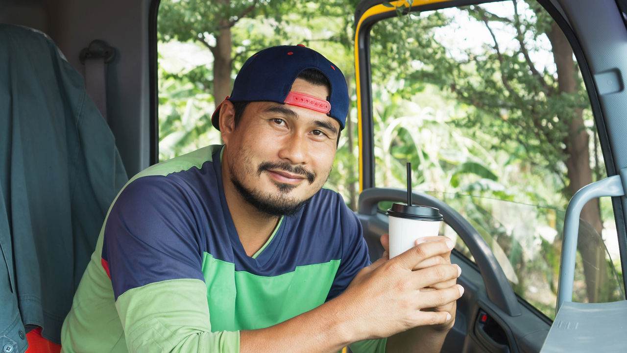 ID 340, Smile Confidence positive optimistic Young Man Professional Truck Driver In Business Long transport. worker male relax holds coffee mug drink in parking lot. owner Transportation delivery semi-truck