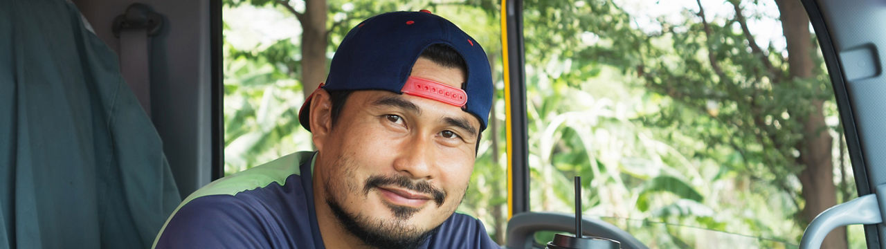 Smile Confidence positive optimistic Young Man Professional Truck Driver In Business Long transport. worker male relax holds coffee mug drink in parking lot. owner Transportation delivery semi-truck