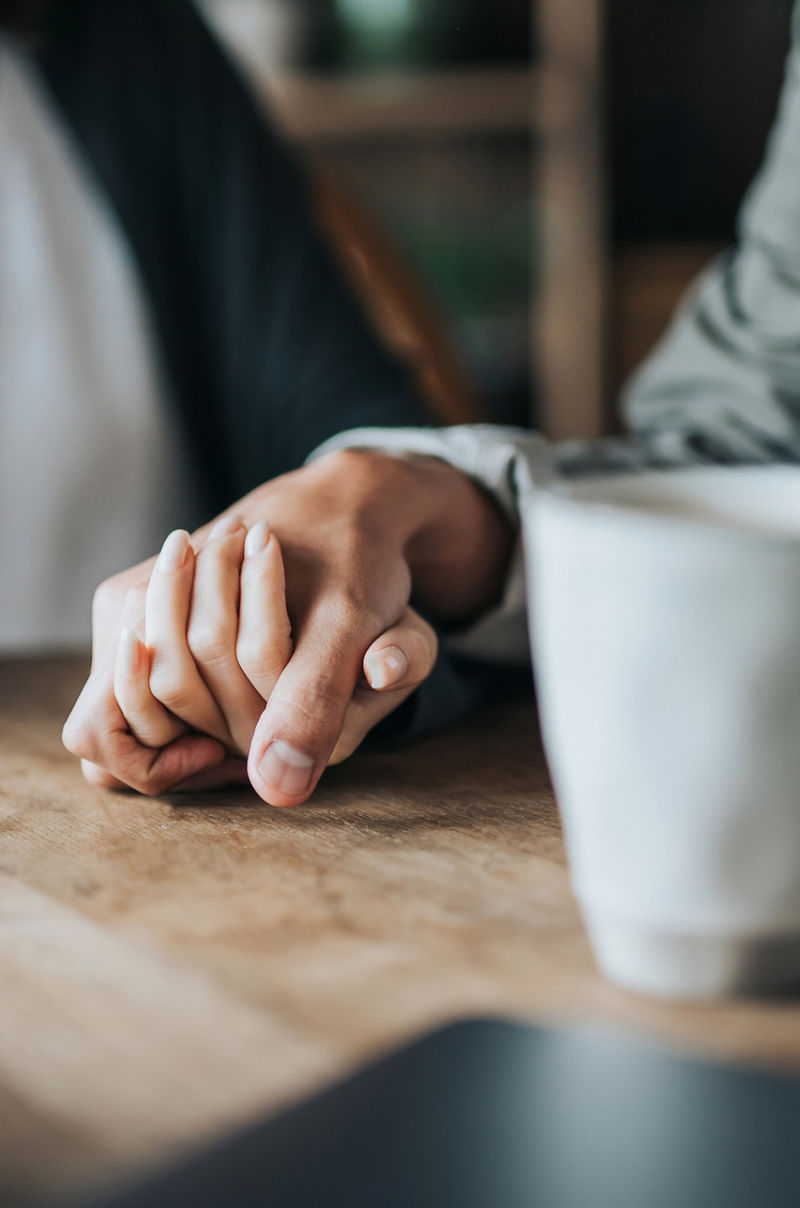 ID 328, Close up of young Asian couple on a date in cafe, holding hands on coffee table. Two cups of coffee and smartphone on wooden table. Love and care concept
