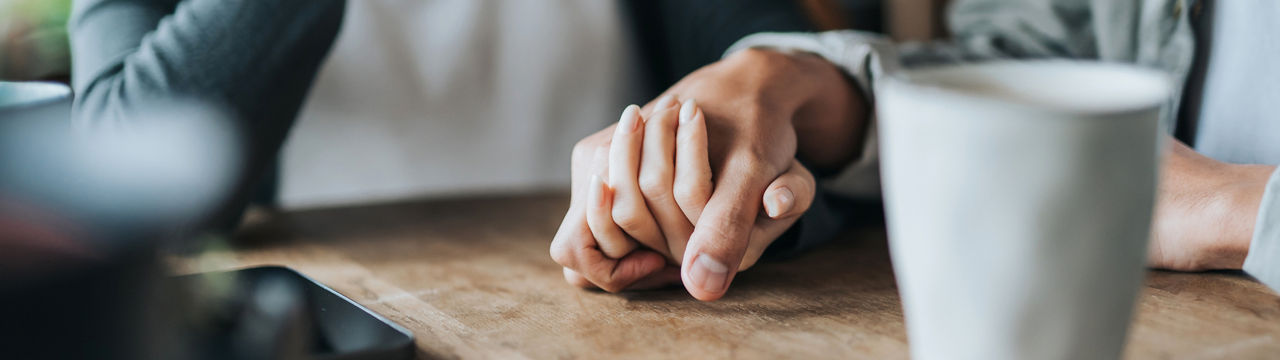 ID 328, Close up of young Asian couple on a date in cafe, holding hands on coffee table. Two cups of coffee and smartphone on wooden table. Love and care concept