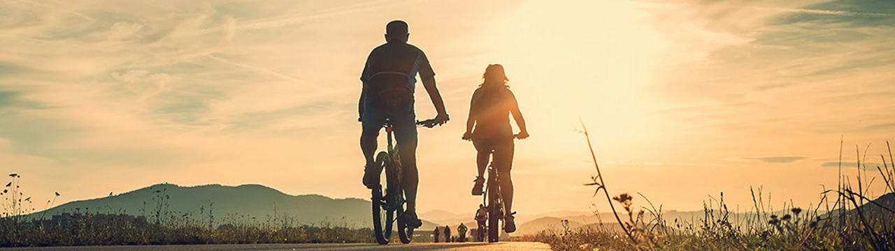 Two bicyclists riding at sunrise