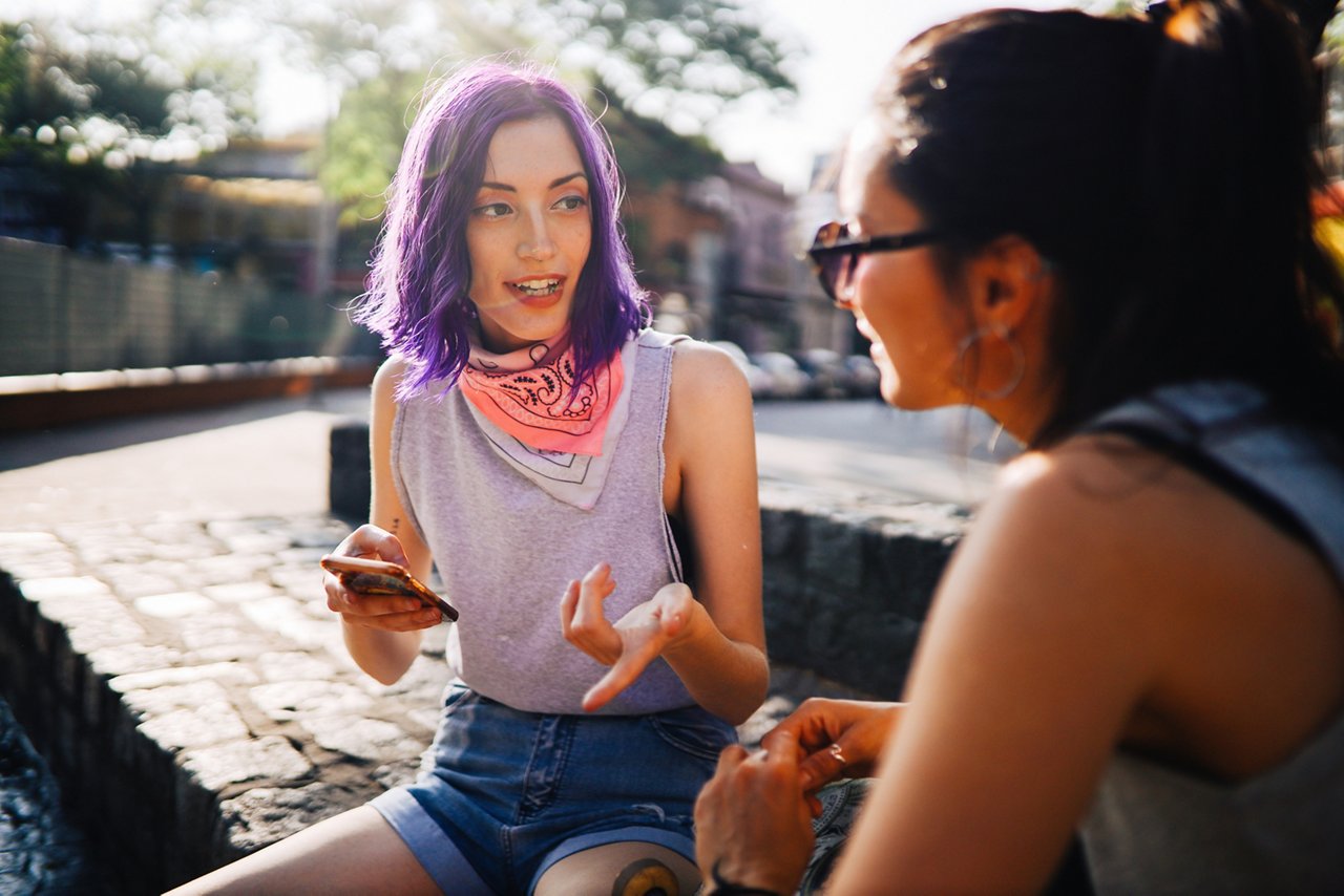 Two young women sitting in the street and talking