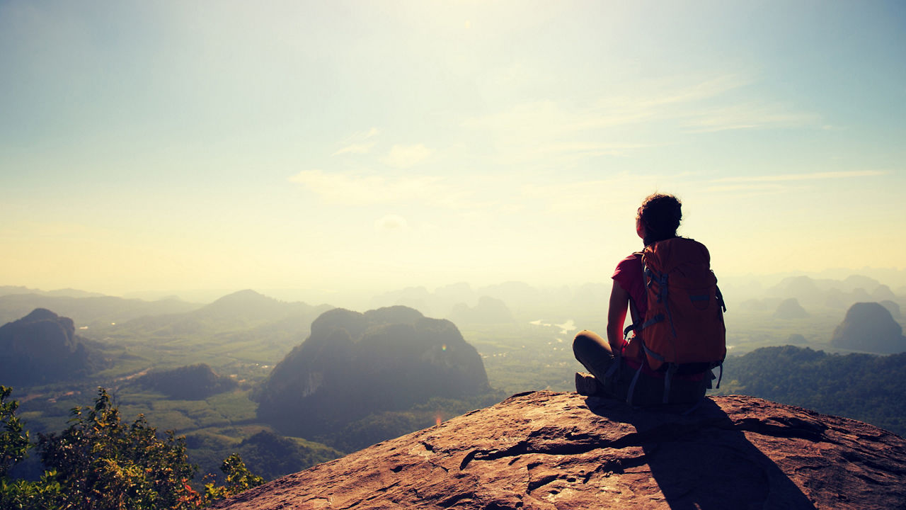 Young woman backpacker hiking at seaside mountain cliff