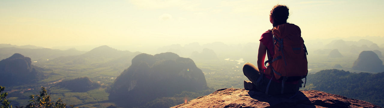 Young woman backpacker hiking at seaside mountain cliff