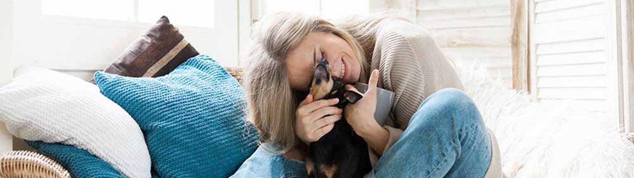 Female nuzzling with small black dog