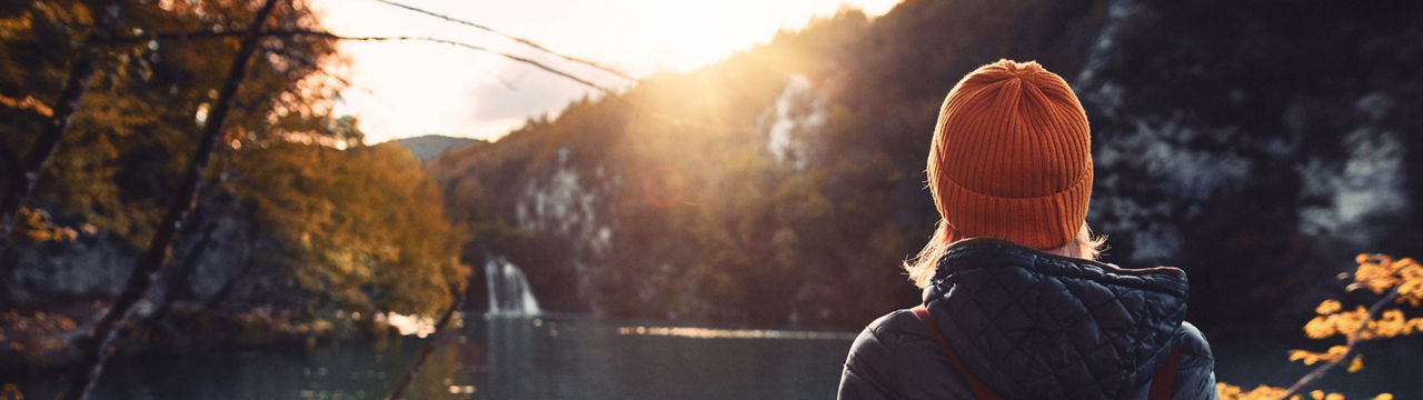 Woman tourist exploring Plitvice Lakes National Park at sunny autumn day