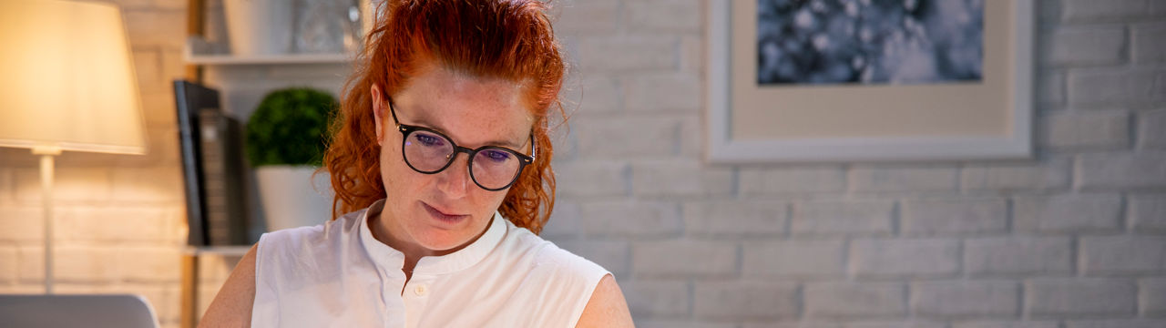 Exhausted, stressed, sleepy woman feeling tired behind her office desk. Working from home. Stressed businesswoman with glasses sitting behind home office desk, cat is watching her