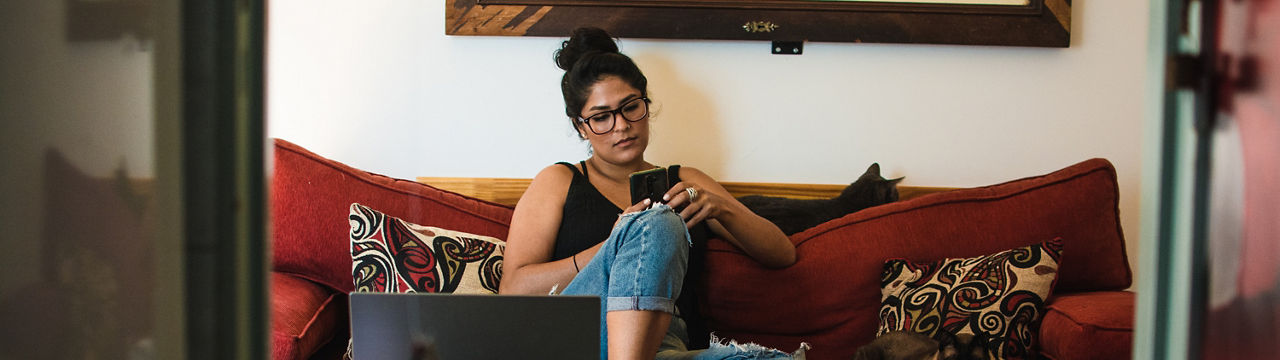 Woman taking break at home on couch and using phone