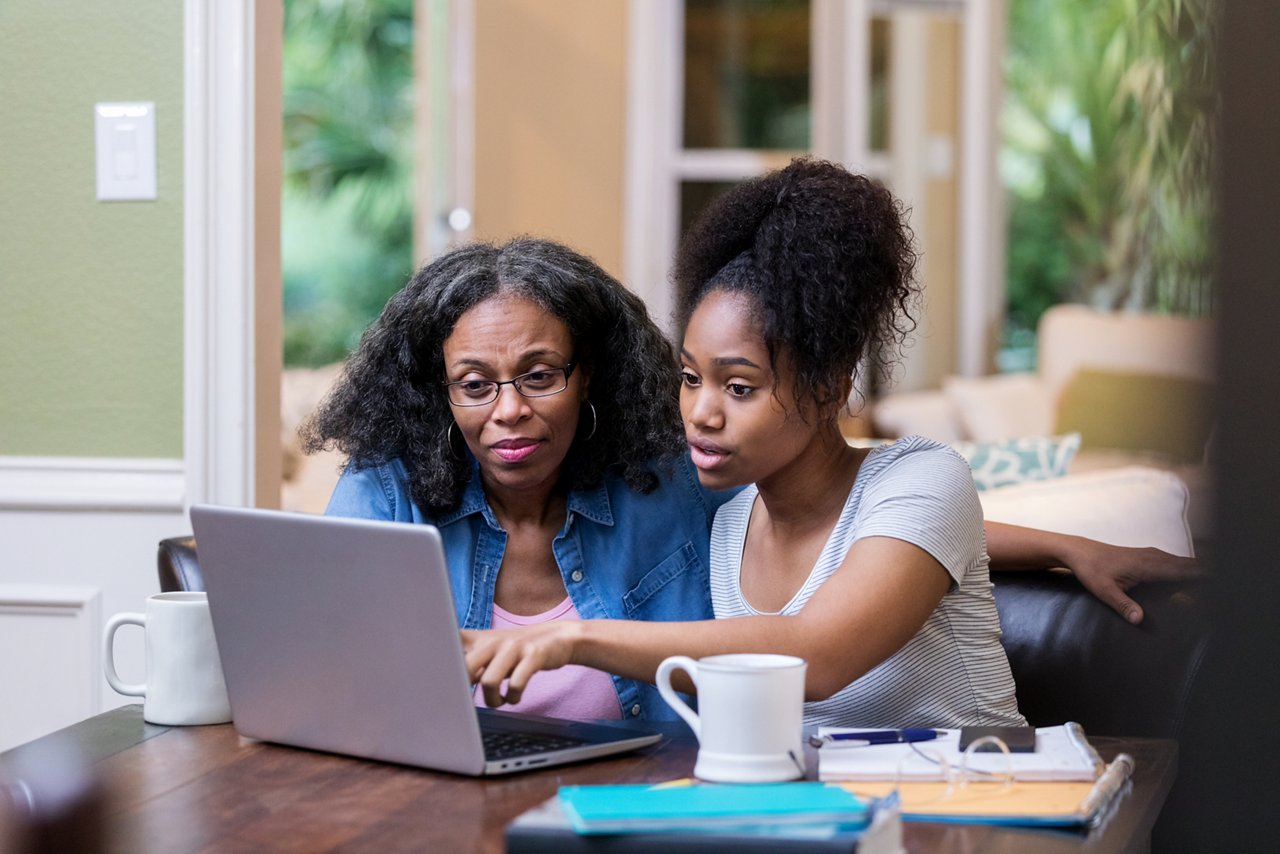 Young woman and her mature mom look at something on a laptop
