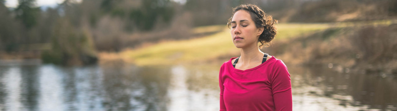 Young Hawaiian mom doing yoga outdoors by lake