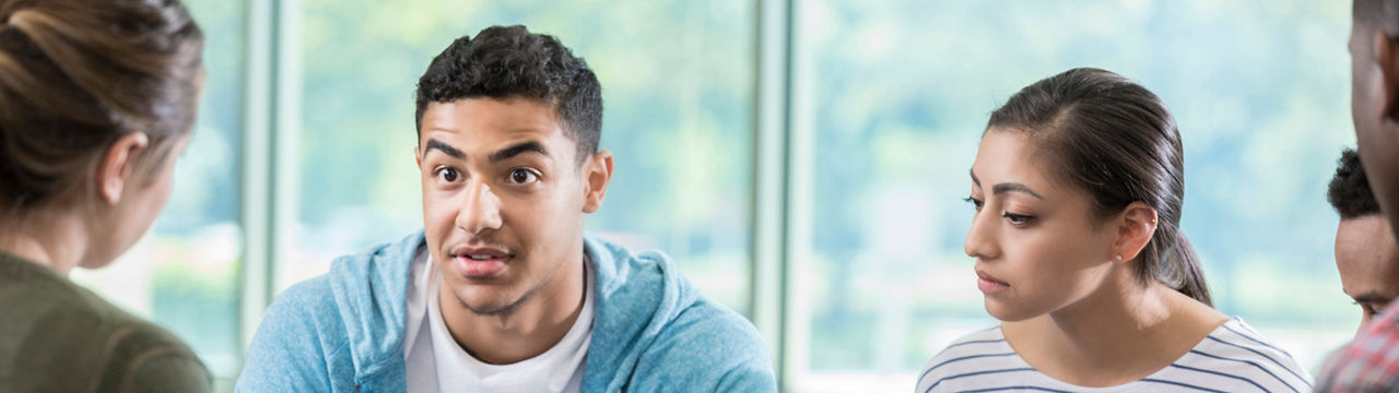 Young African American man gestures as he discusses something in a group therapy session