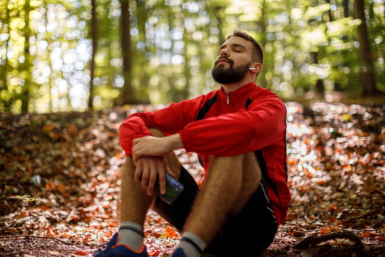 man sitting in forest with eyes closed