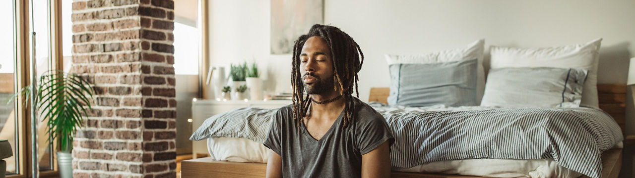 Young men practicing yoga at home. He is in bedroom and doing yoga, first thing in the morning