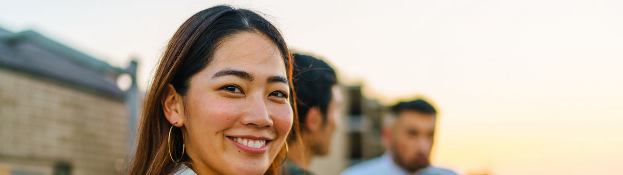 A portrait of a young woman looking at the camera during social gathering with friends at the balcony