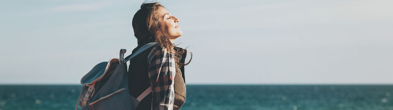 Young woman with eyes closed enjoying the air and sea on a sunny day