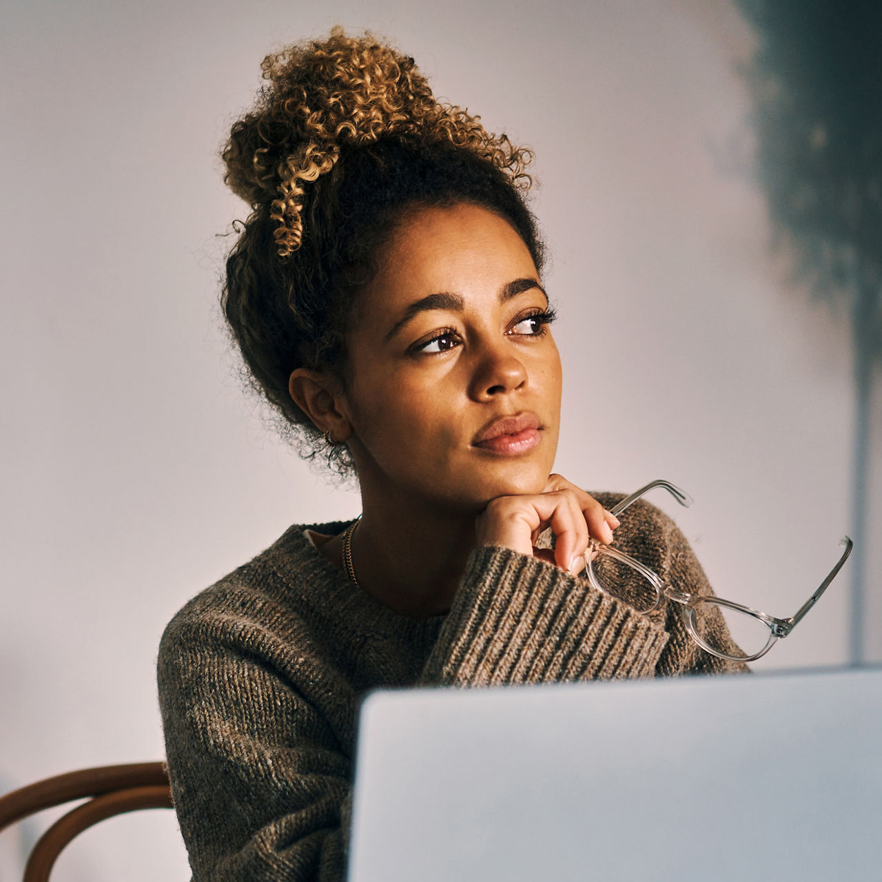 Shot of a young woman looking thoughtful while using a laptop at home