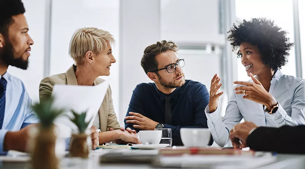 Four technological innovators sit at a table together, discussing sustainable solutions for their company