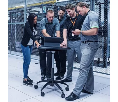A group of people in a datacenter looking at a computer.