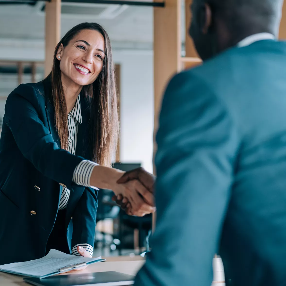 A woman and man secure their innovative partnership with a handshake and a smile