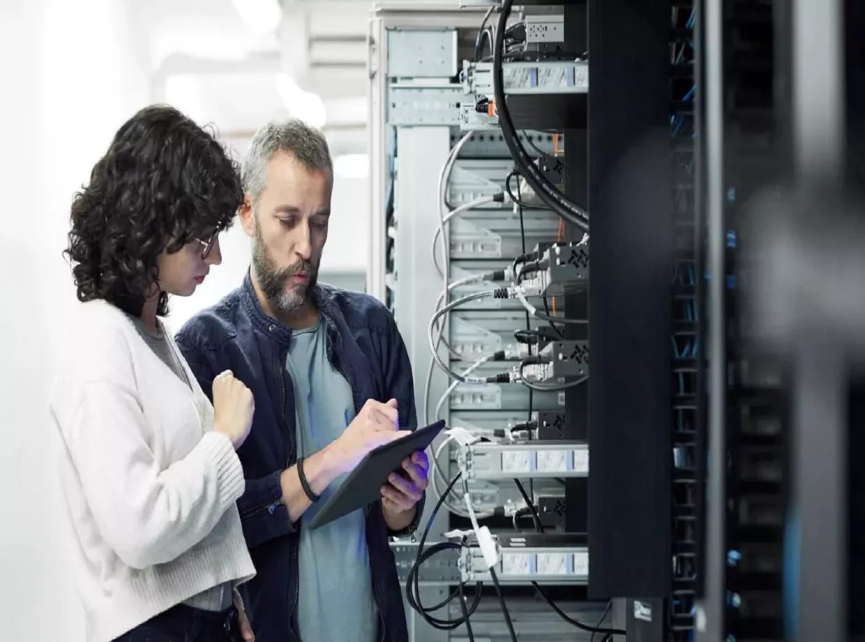 A woman and man look over data on a clipboard together while standing in a sustainable server room