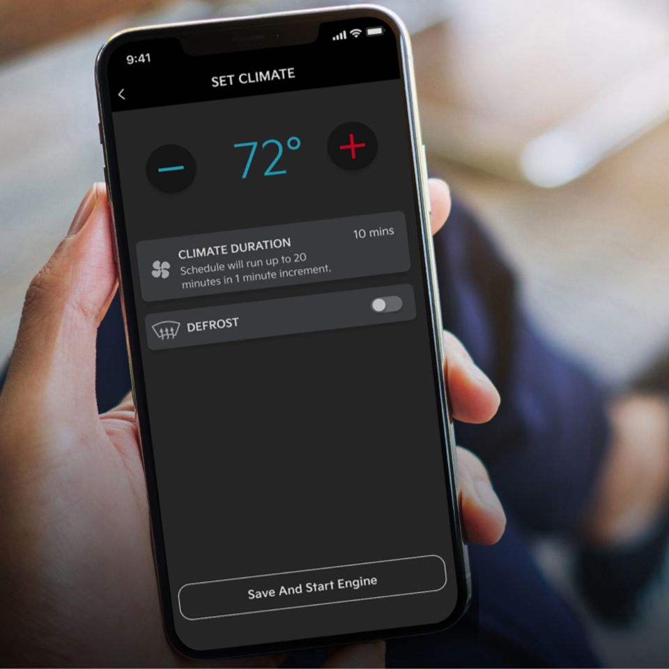A hand holding a phone with a screen that displays the car temperature settings