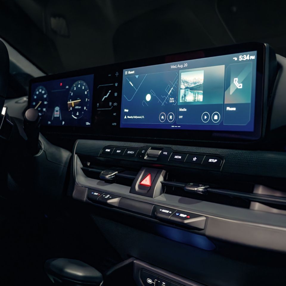 An interior shot of the 2026 K4 Hatchback GT-Line Turbo showcasing the digital cockpit with a wide touchscreen display integrating infotainment and vehicle controls, with a desert landscape visible through the windshield in the background.