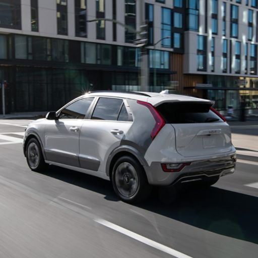 2026 Kia Niro EV cruising down a city road, rear three-quarter view