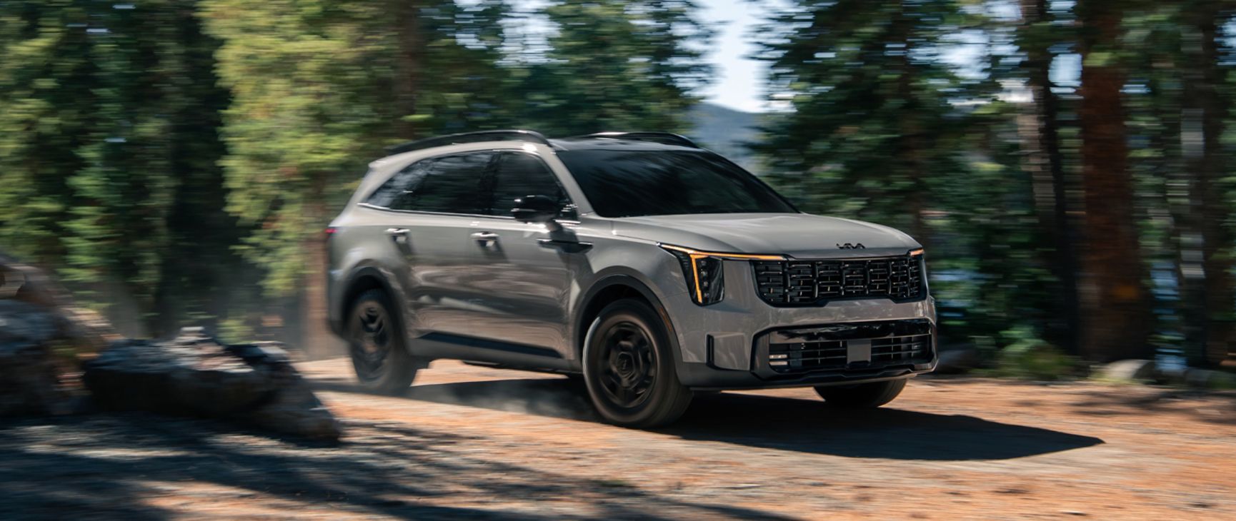 2026 Kia Sorento, three-quarter front view, towing a speed boat while driving through the forest