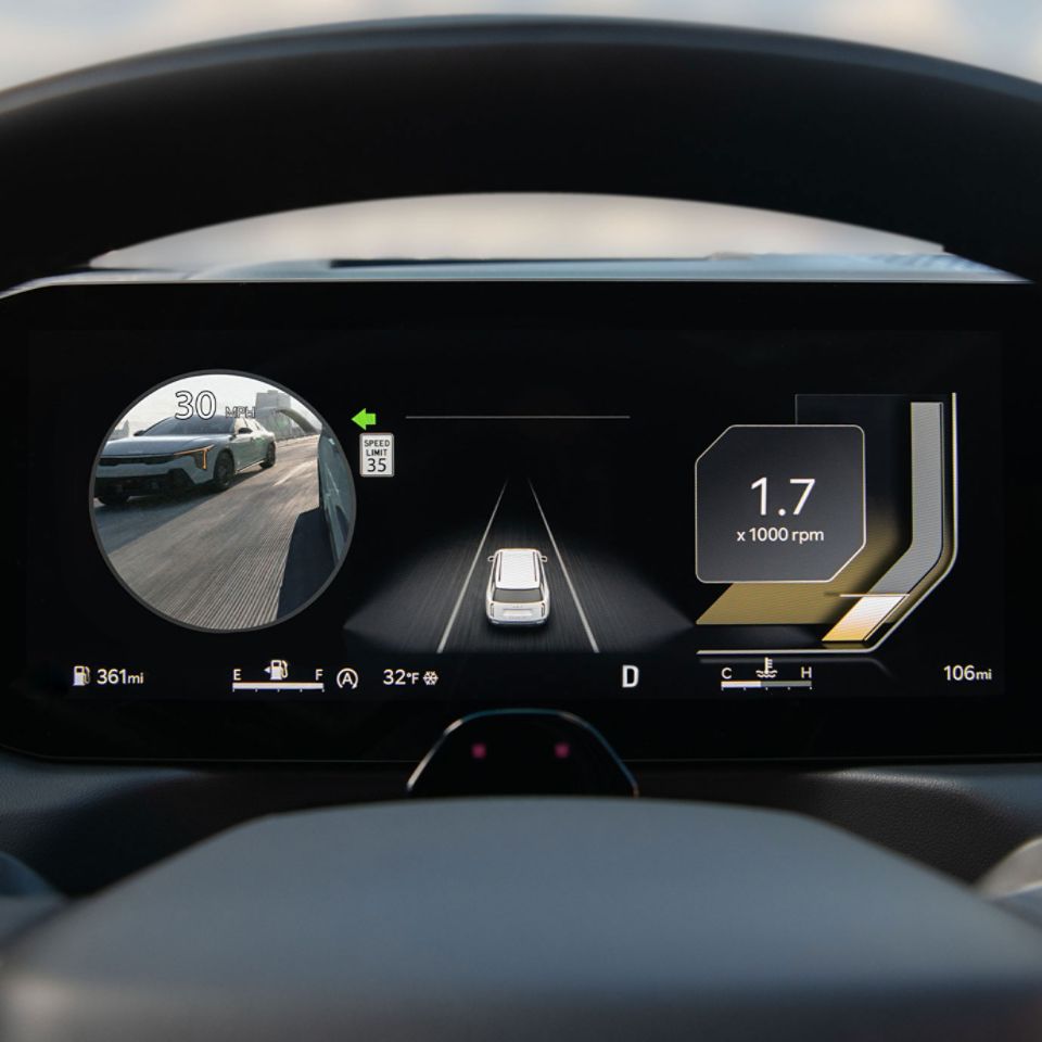 Zoomed in view of the digital dashboard that features the speedometer on the left, the vehicle image in a lane in the middle, and a monitor that displays a live view of the car's blind spot on the right.