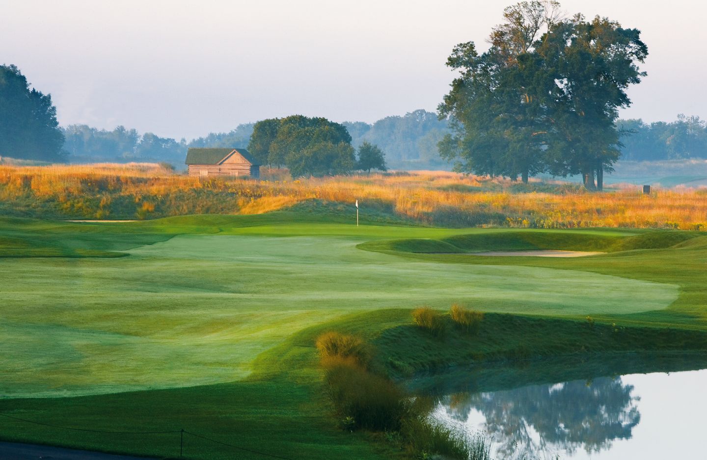 The first hole of the Meadow Valleys course with the green in the distance and a sand trap to the right of the green. 