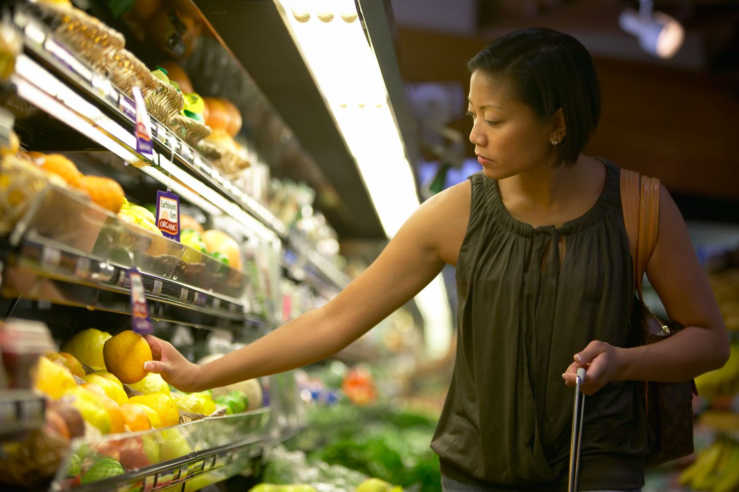 A lady selecting produce at a grocery store