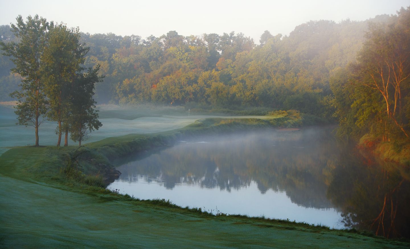 The green of hole 11 on the River Course in the distance with morning fog in fall. 